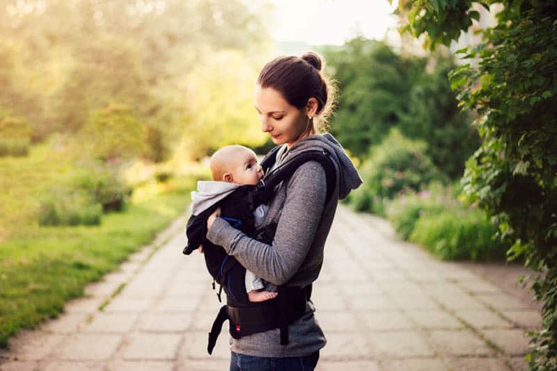 mother walking in the park with baby in carrier