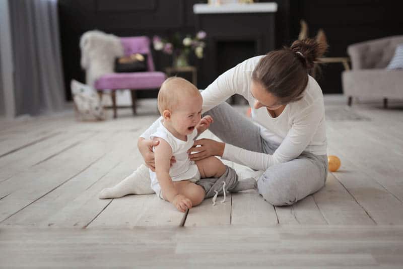 mother with crying baby on the floor