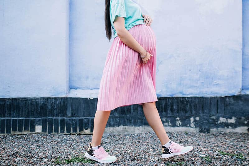 pregnant woman in pink skirt walking outdoor