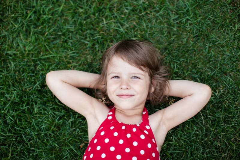 smiling little girl lying on green grass
