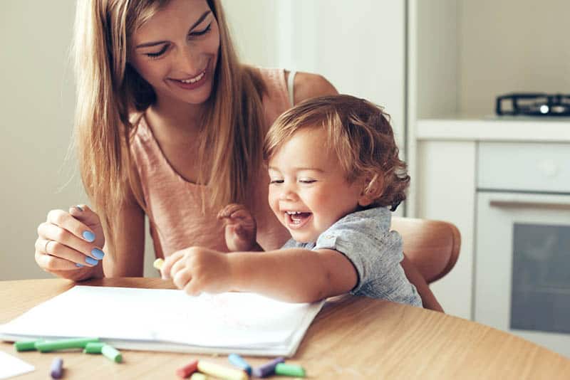 smiling mother drawing with her baby on the table