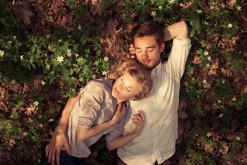sweet couple lying on the grass between flowers