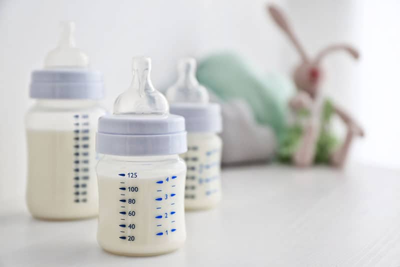 three glass baby bottles full of milk