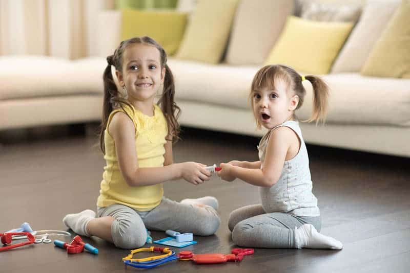 two sisters playing on the floor with toys