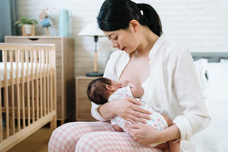 woman breastfeeding baby in bedroom