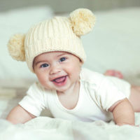 cute baby with winter hat lying on the bed
