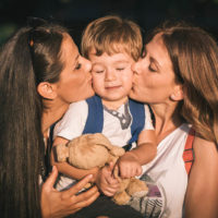 aunts kissing their little nephew on the cheek