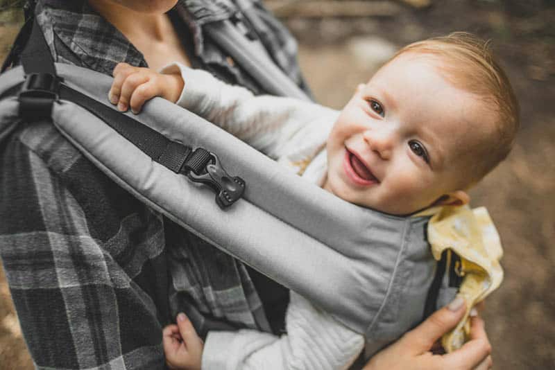 adorable baby smiling in the carrier on his mother