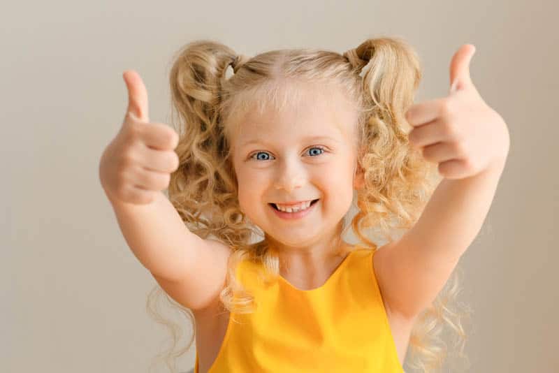 adorable little girl showing double thumbs-up