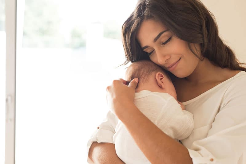 beautiful young mother holding her newborn baby on the chest