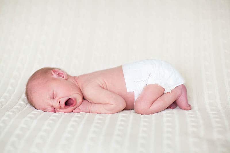cute newborn baby in diapers lying on the bed