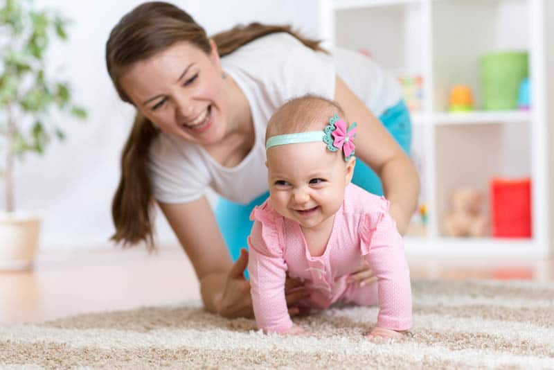 happy mother catching her baby crawling on the floor