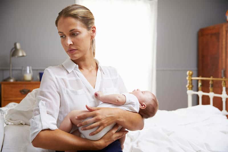 worried mother holding a baby in the bedroom