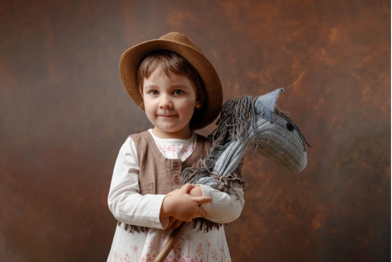 little girl in a cowboy hat holding a horse toy