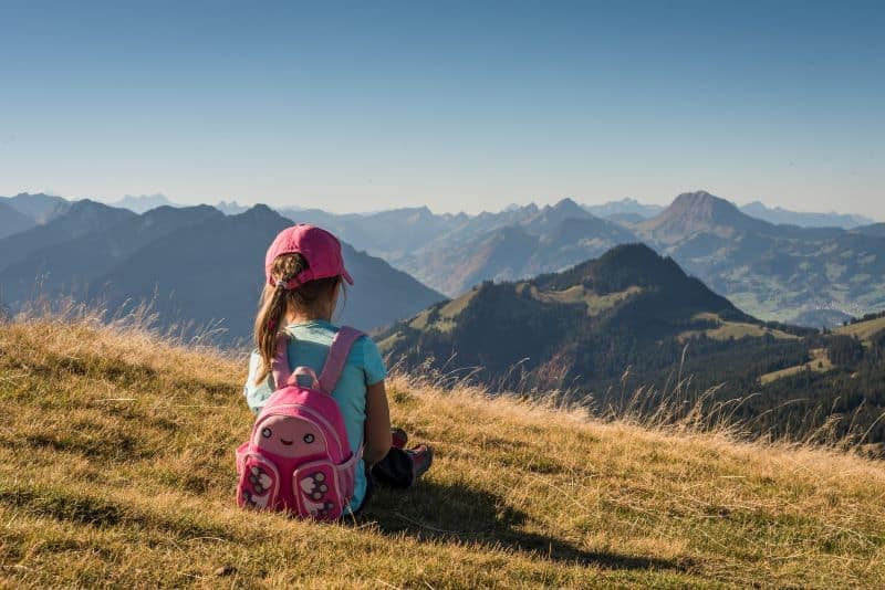 little girl with a backpack on a hill