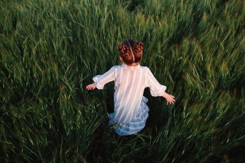 little girl walking through a grass field