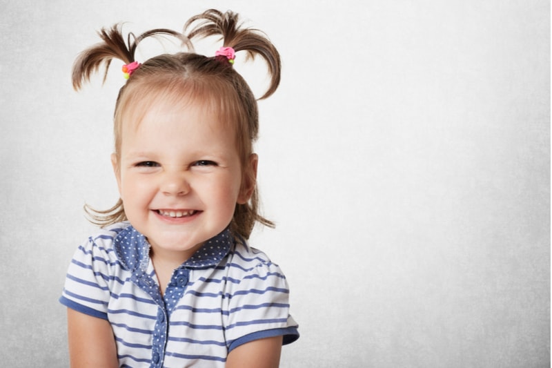 little girl with pigtails smiling